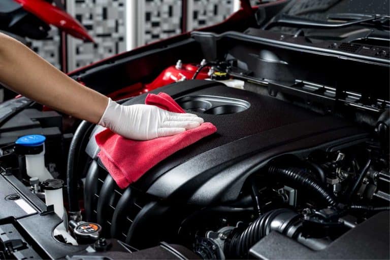 Hand of auto detailer with glove cleaning and polishing engine compartment