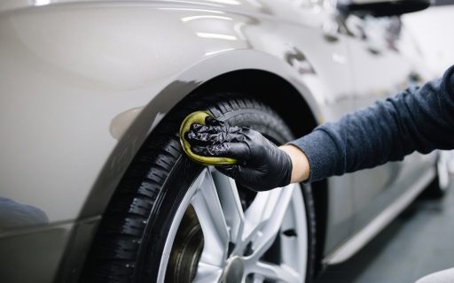 Hand of auto detailer with glove polishing car tire
